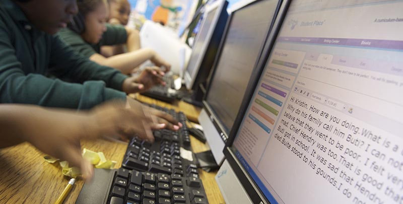 Hands typing on a keyboard with text on screen.