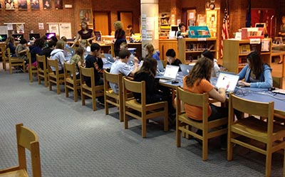A library setting with many students working at laptops.
